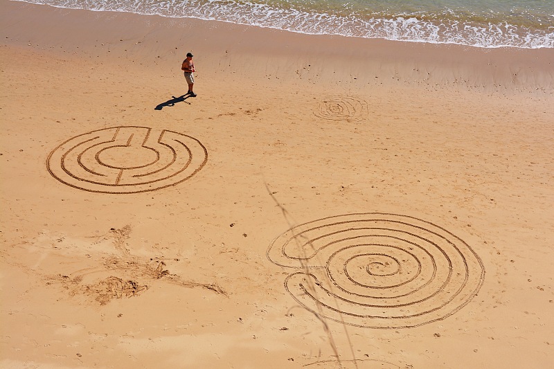 Narysowane patykiem kręgi na plaży.